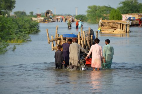 Men walk along a flooded road with their belongings, following rains and floods during the monsoon season in Sohbatpur, Pakistan August 28, 2022. REUTERS/Amer Hussain NO RESALES. NO ARCHIVES.