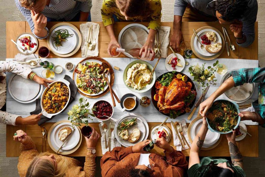 A group of friends and family join around the table for a lovely Thanksgiving meal.