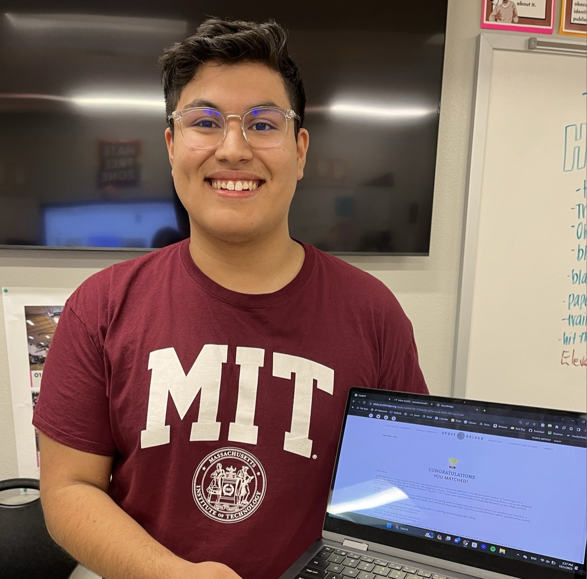 Marco Arevalo smiles with his laptop showing his QuestBridge portal informing him of his acceptance and full-ride scholarship to MIT. 