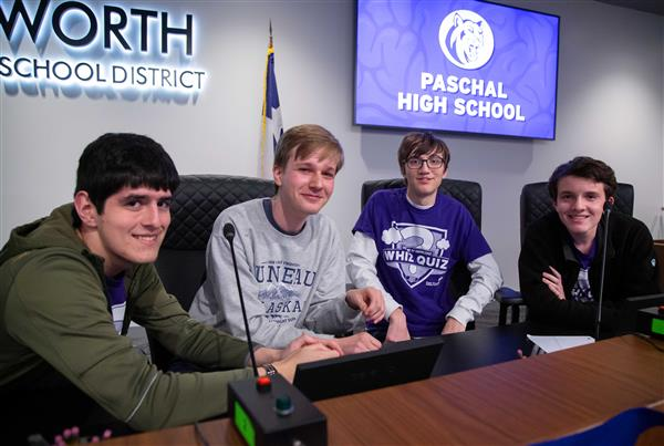 Paschal Whiz Quiz team members Jude White (left), Jonthan Feldman (middle left), Jesse Durham (middle-right), and Spencer Morgenweck (right) smile mid-match. (Slide 65/114 https://www.fwisd.org/domain/1480)
