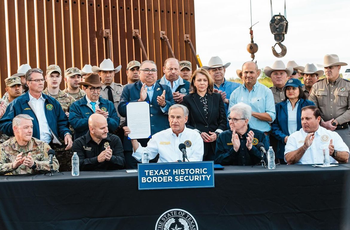 Texas Governor Greg Abbott holding up signed SB4 bill criminalizing illegal entry into the state during Brownsville Texas Historic Border Security spectacle. (Photo taken Dec. 18th, 2023, sourced from @governorabbott on Instagram.)