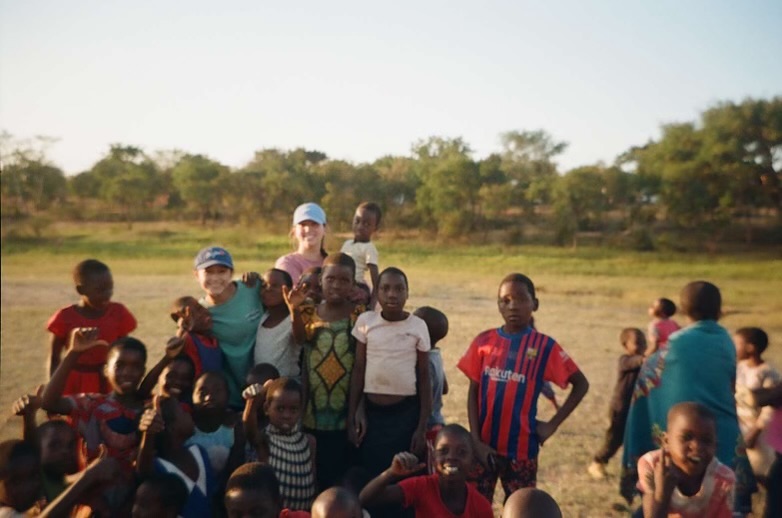 Gabby Price (on the left) and Cameron McAllister (on the right) posing with a happy group of children in Malawi. 