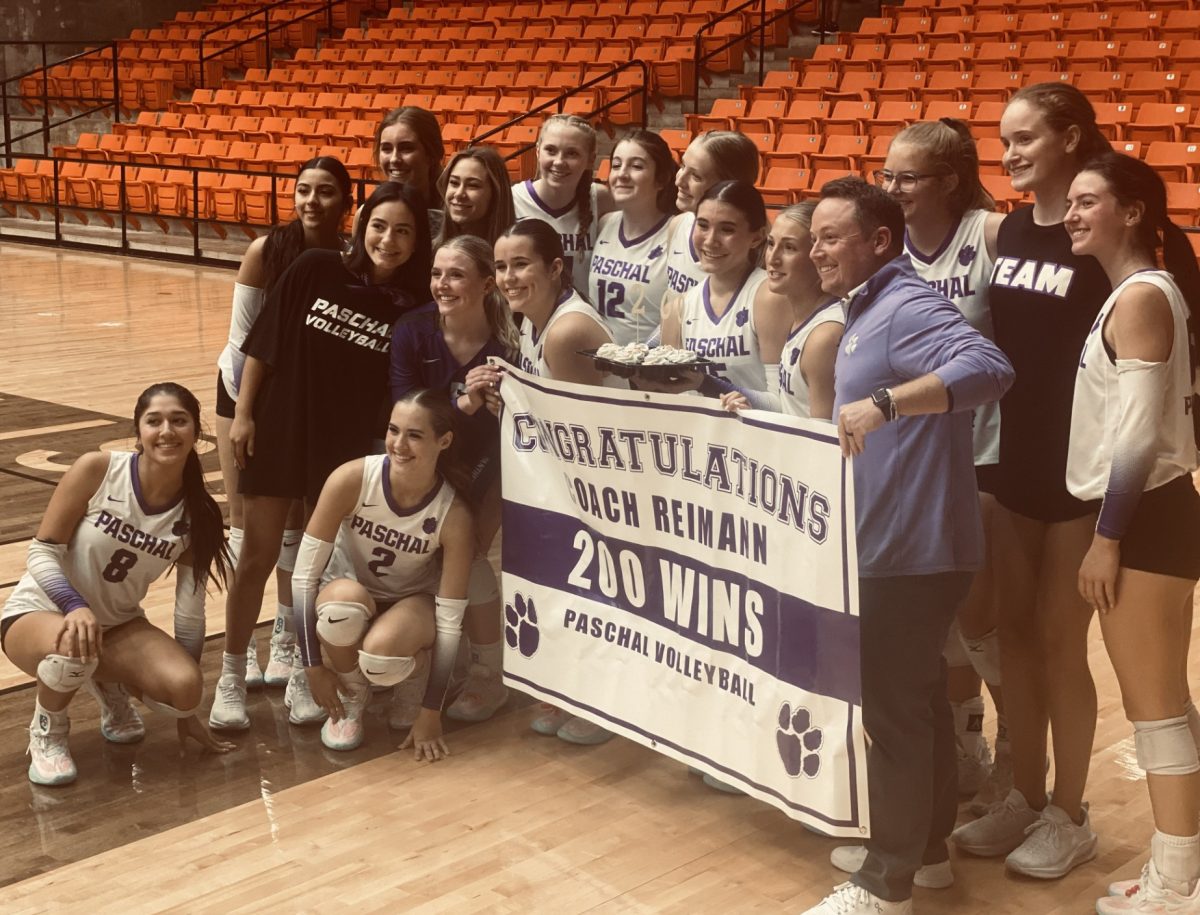 The PHS volleyball team happily stands with their coach, Mr. Reimann, as they celebrate his 200th career win. 